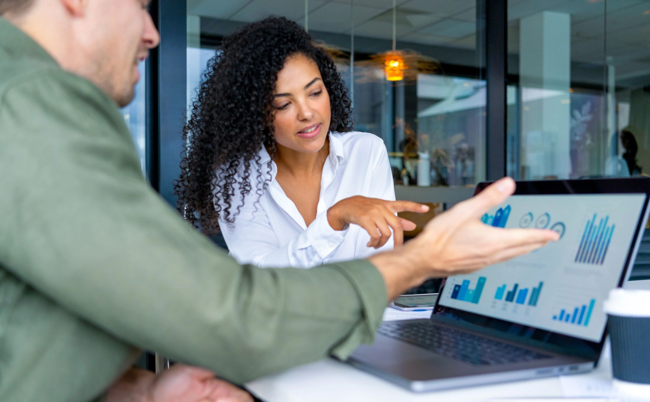 Two professionals reviewing analytics on a laptop in an office meeting