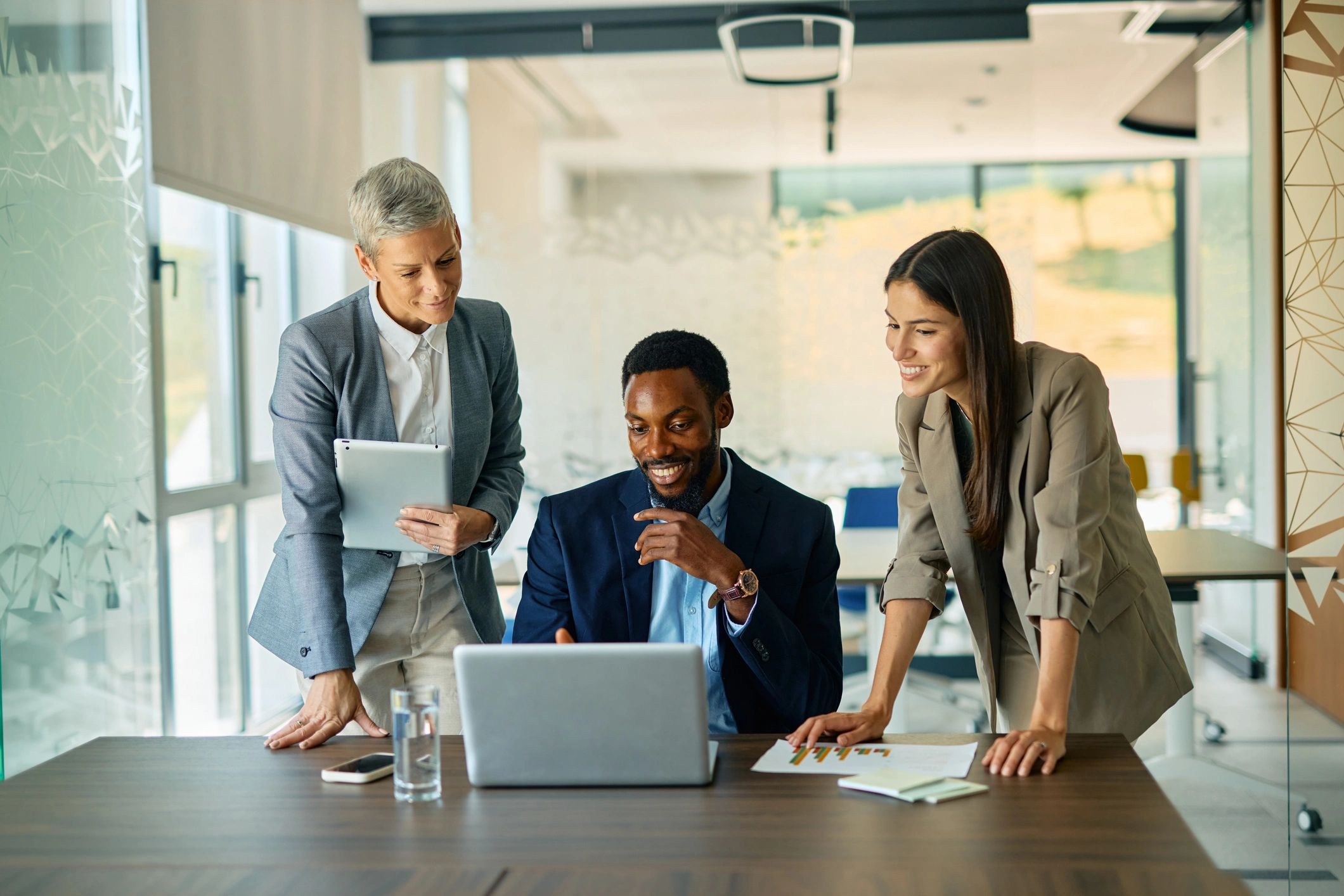 Marketing team collaborating around a laptop in a modern office
